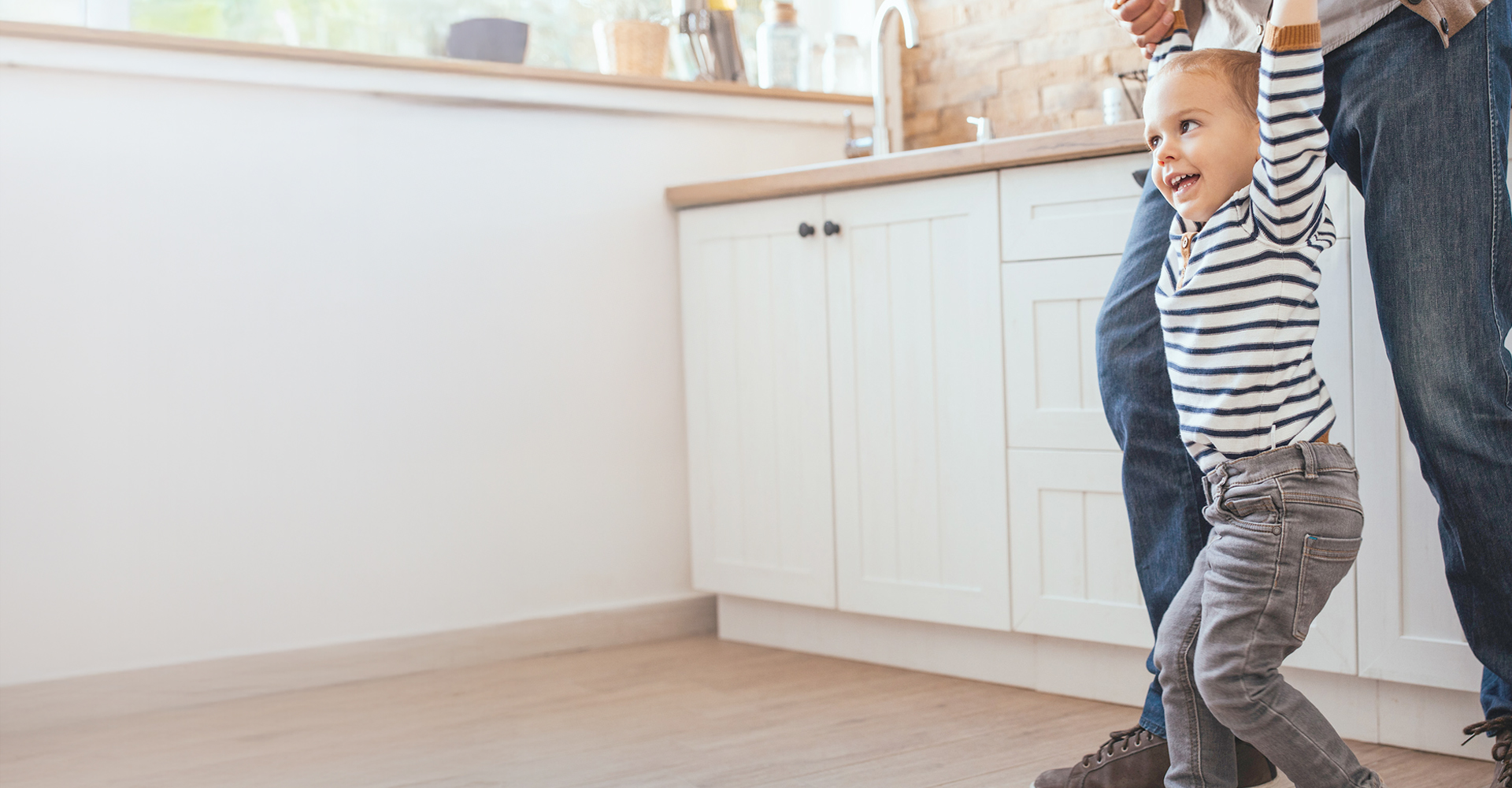 Dad pushing Daughter in Cardboard box on Hardwood Floors in Home.